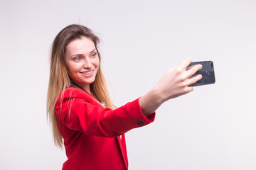 Naklejka premium Young blond woman making selfie in studio