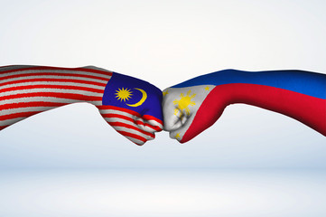 Fist bump of Malaysian and Filipino  flags.
Two hands with painted flags of Malaysia and...