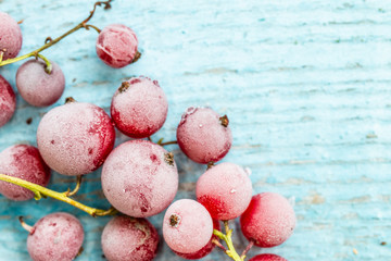 frozen berries of red currant on blue colored wooden background, top view. macro.