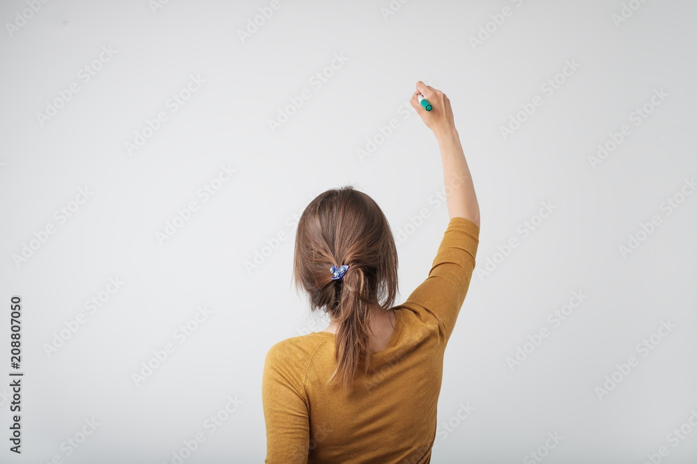 Wall mural A european woman writing something isolated on white background. Concept of studying at univercity or college