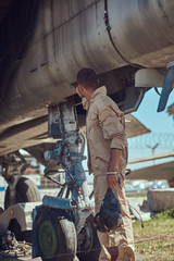 Mechanic in uniform standing near a war fighter-interceptor in an open-air museum.