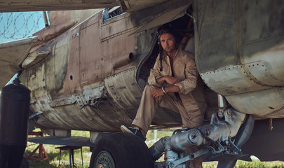 Mechanic in uniform and flight helmet carries out maintenance of an old military bomber in an open-air museum.
