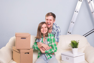 Happy young cheerful couple sitting on the sofa in new apartment after moving in.