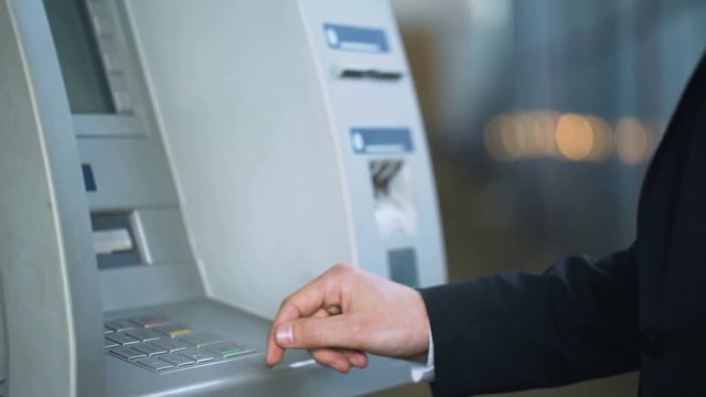 Client entering pin code on ATM and receiving Russian rubles, banking services