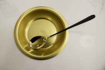 a gold bowl and spoon in marble