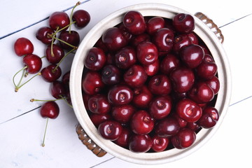 Fresh sweet cherry in bowl on wooden background top view