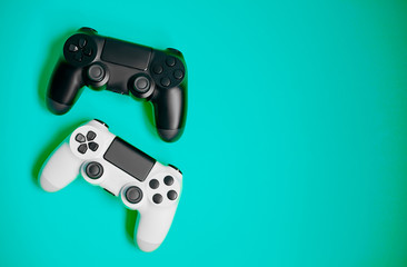 Computer game competition. Gaming concept. White and black joysticks on green background.