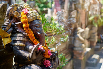 Religious decoration. Traditional stone sculpture of Ganesha god with flowers in the backyard....