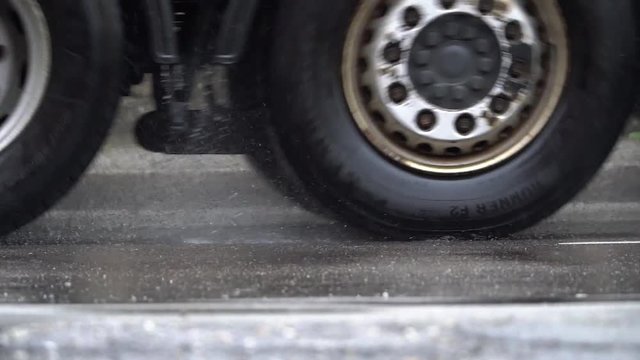 Slow motion-/Zeitlupen-Aufnahme einer Stra&szlig;e an einem regnerischen Tag. Ein LKW und eine Person mit Behinderung kreuzen. Standpunkt auf Strassenniveau