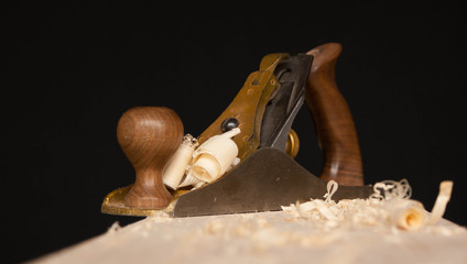 the plane on the workbench on black background , wood processing