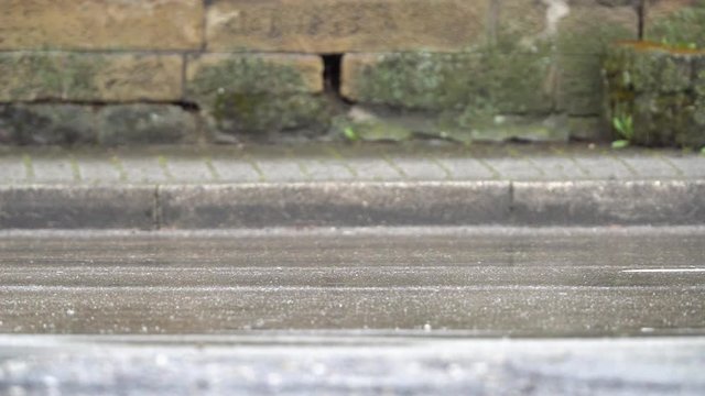 Slow motion-/Zeitlupen-Aufnahme einer Stra&szlig;e an einem regnerischen Tag. Autos fahren durchs Blickfeld. Standpunkt auf Strassenniveau