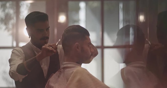 Young stylish barber cutting client's hair in old-fashioned barber shop