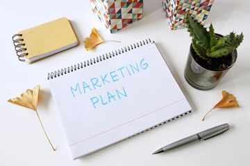marketing plan written in a notebook on white table