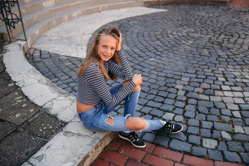 Fototapeta premium young teenage poses to photographer. blonde girl in jeans and blouse