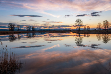 Sunset over calm lake , sky reflection in water.