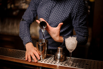 Barman pouring a portion of vodka into the shaker