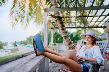 Technology and travel. Working outdoors. Freelance concept. Pretty young woman using laptop in cafe...