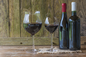 Wine tasting concept: two bottle of red wine and wineglasses on rustic background