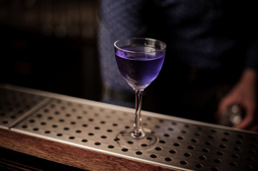 Elegant glass filled with violet colored sweet and strong summer cocktail