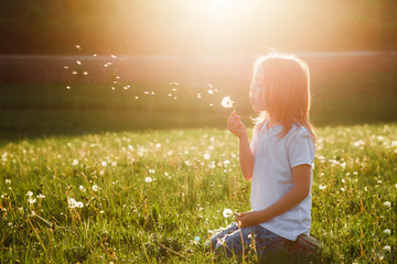 Little girl blowing dandelion.