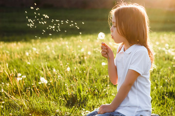 Little girl blowing dandelion.
