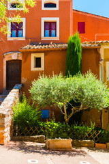 Fototapeta na wymiar Colorful ochre houses and garden in the Roussillon village, Provence, France