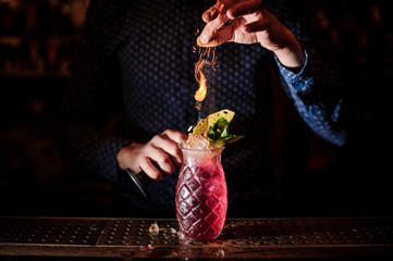 Barman adding spices into the fresh and sweet strawberry mojito summer cocktail with a smoke note