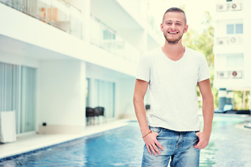 Vacation concept. Happy young man near swimming pool.