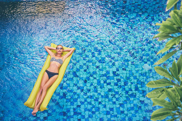 Enjoying suntan. Tropical vacation concept. Top view of slim young woman in bikini on the yellow...