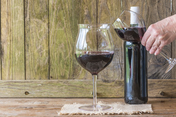 Tchin-tchin: hand holding a glass of red wine making tchin tchin with another glass of red wine on rustic background