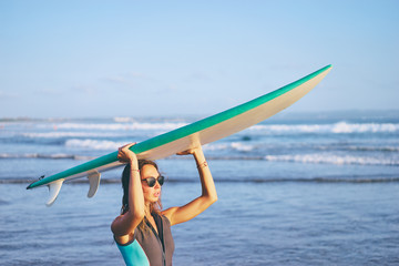 It's time for surfing! Hobby and vacation. Pretty young woman holding surf board on the sea beach.