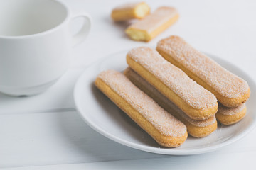 Biscuit Savoiardi with a cup of coffee on the kitchen table.