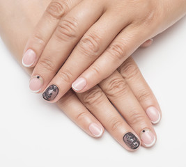 Cute manicure on female hands. Woman hands with black and white design manicure on vintage wooden background. Nails and skin treatment. Matte manicure on female hands.