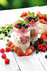 Glass jar of homemade granola with yogurt and fresh berries
