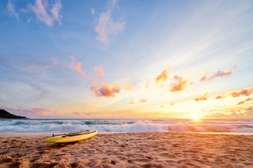 Beautiful landscape. Sunset on the sea beach with lifeguard surf board on sand.