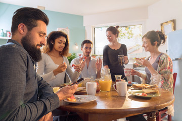 Group of multi-ethnic friends gathered around a table for breakfast
