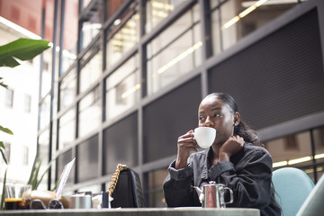 Black girl having a cup of tea on a modern terrace