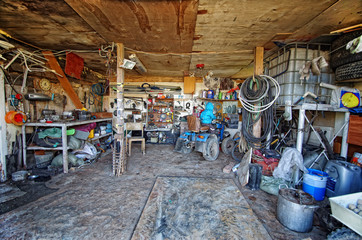 Inside a messy and cluttered garage shed with tools, cans, garden equipment in organised chaos