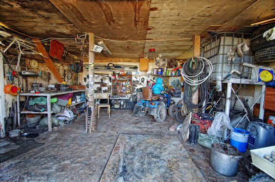 Inside A Messy And Cluttered Garage Shed With Tools, Cans, Garden Equipment In Organised Chaos