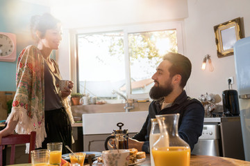 Cheerful couple having breakfast in the kitchen of their house