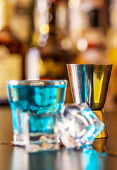 Popular blue drink shot kamikaze on the background of the bar with bottles, a refreshing drink