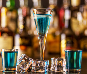 Popular blue drink shot kamikaze on the background of the bar with bottles, a refreshing drink