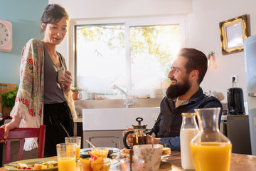 Fototapeta na wymiar Cheerful couple having breakfast in the kitchen of their house