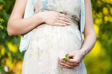 Close-up image of pregnant woman touching her belly with hands