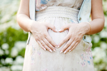 Close-up image of pregnant woman touching her belly with hands