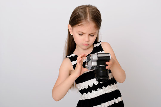 Little beautiful girl viewing settings on her retro dslr photo camera.