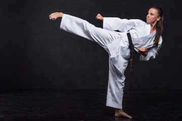  A girl in a white kimono with a black belt on a dark background