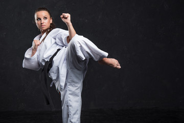  A girl in a white kimono with a black belt on a dark background © Siarhei Kulikou