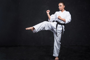 Fototapeta na wymiar A girl in a white kimono with a black belt on a dark background