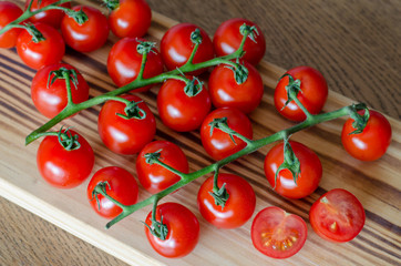 A branch of cherry tomatoes on wooden cutting board. selective focus. top view.